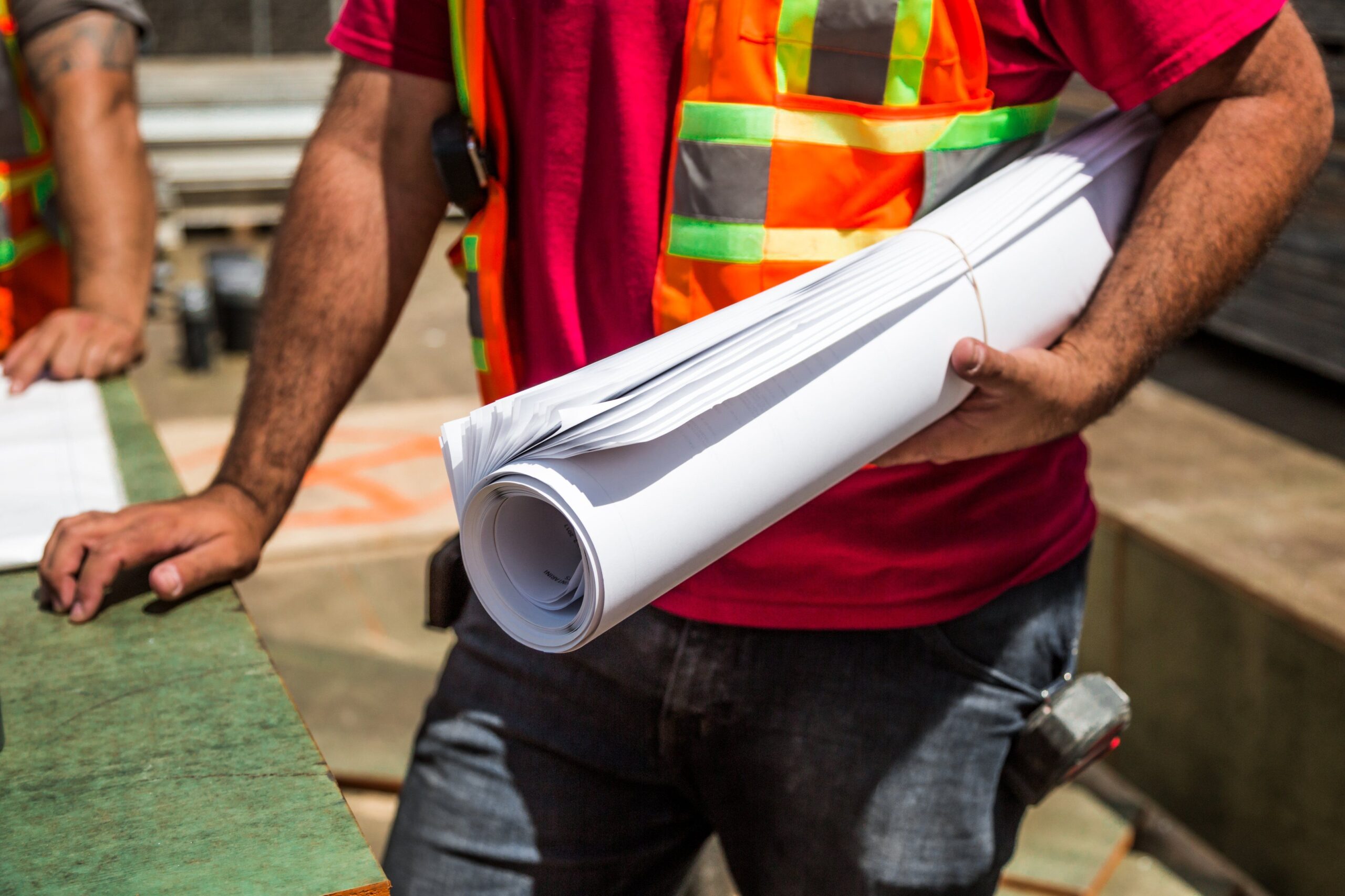 Construction workers in safety vests holding a blueprint