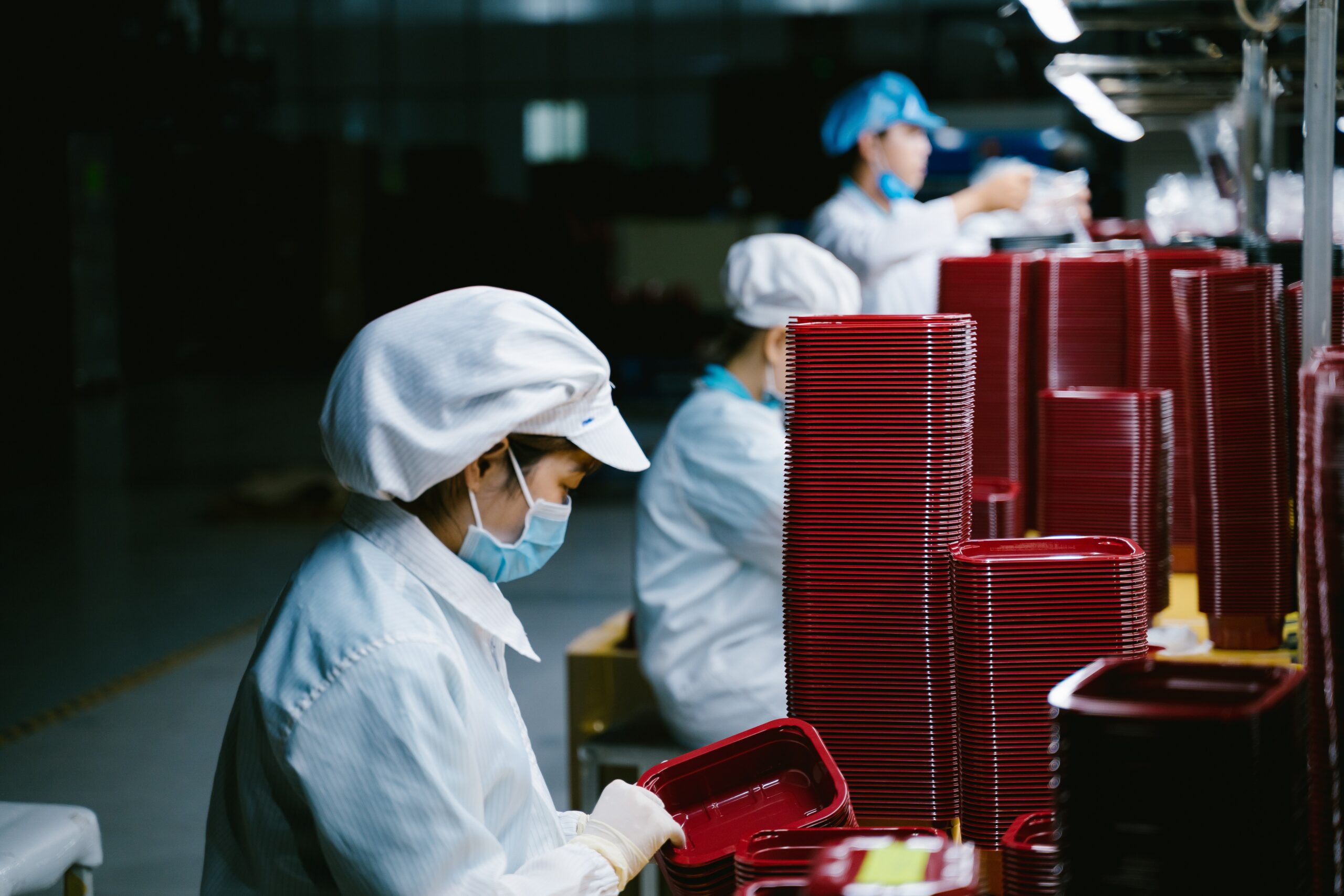 Woman in protective uniform and mask working on factory line