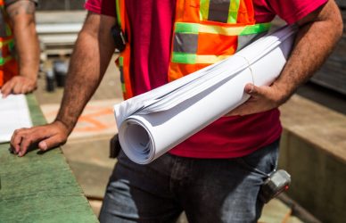 Construction workers in safety vests holding a blueprint