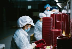 Woman in protective uniform and mask working on factory line