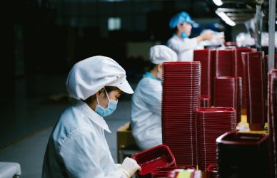 Woman in protective uniform and mask working on factory line
