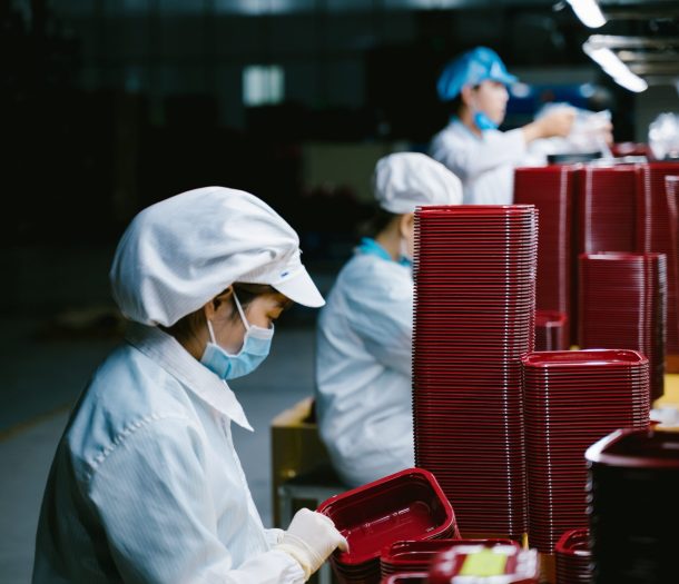 Woman in protective uniform and mask working on factory line